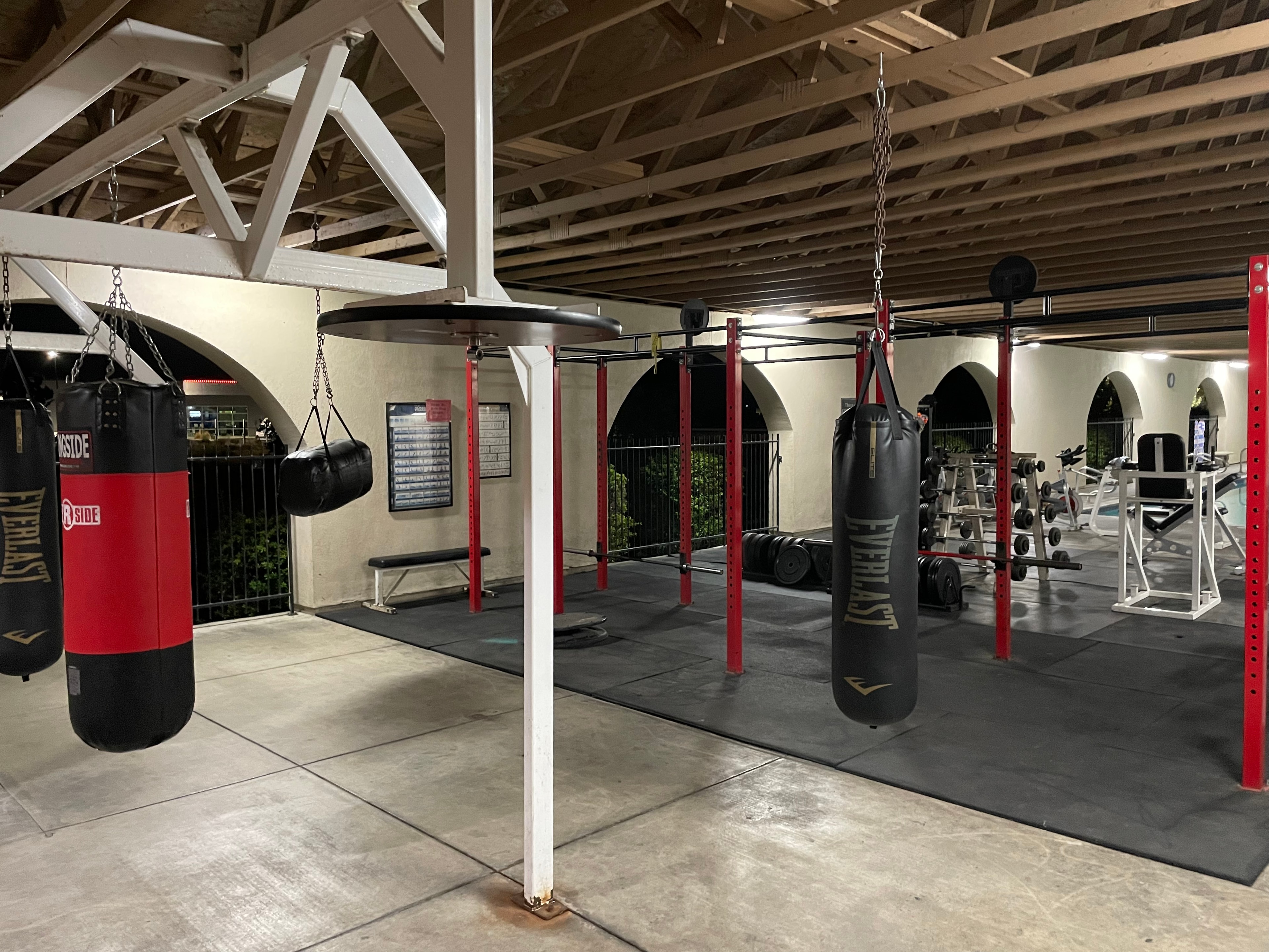 Boxing area with Everlast heavy bags and powerlifting racks